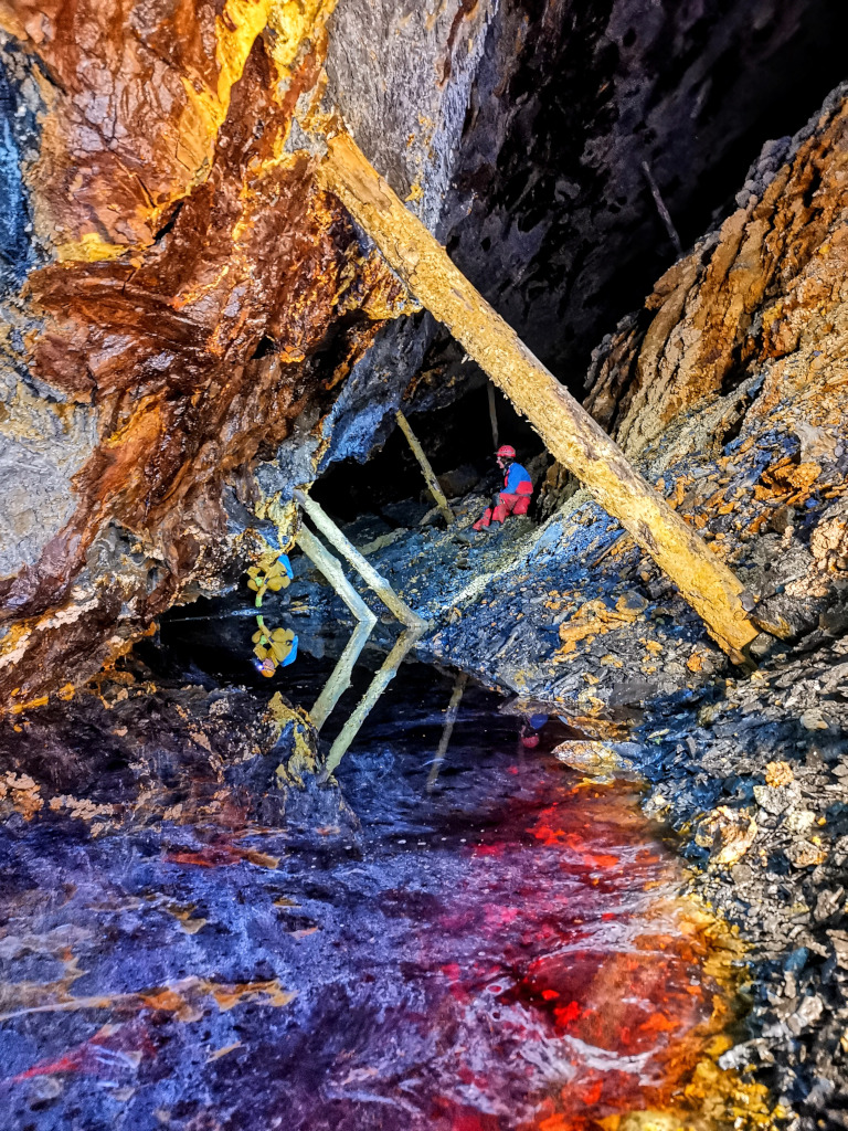 Heather Simpson and Rob Nevitt in Cae Coch Sulfur Mine, North Wales. 
	The colours are real. Photo © Gaz McShee. April 2023.